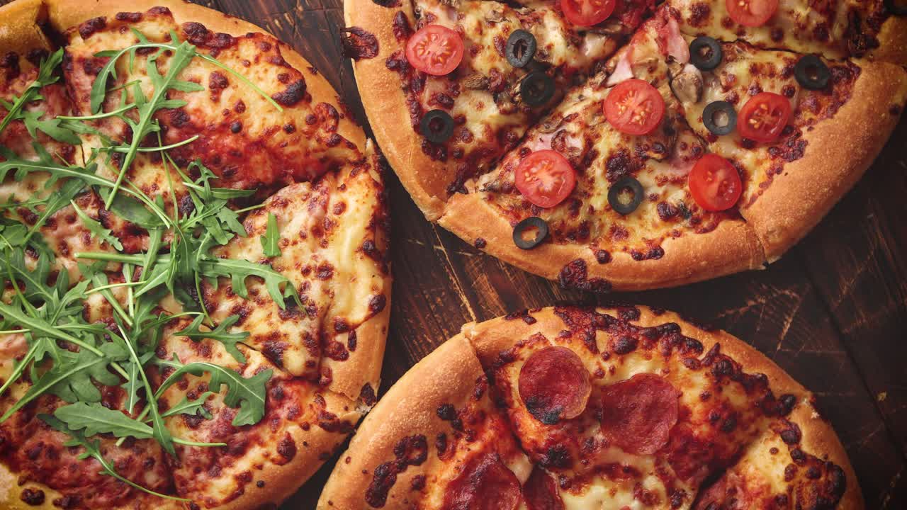 Various kinds of pizzas placed on wooden table
