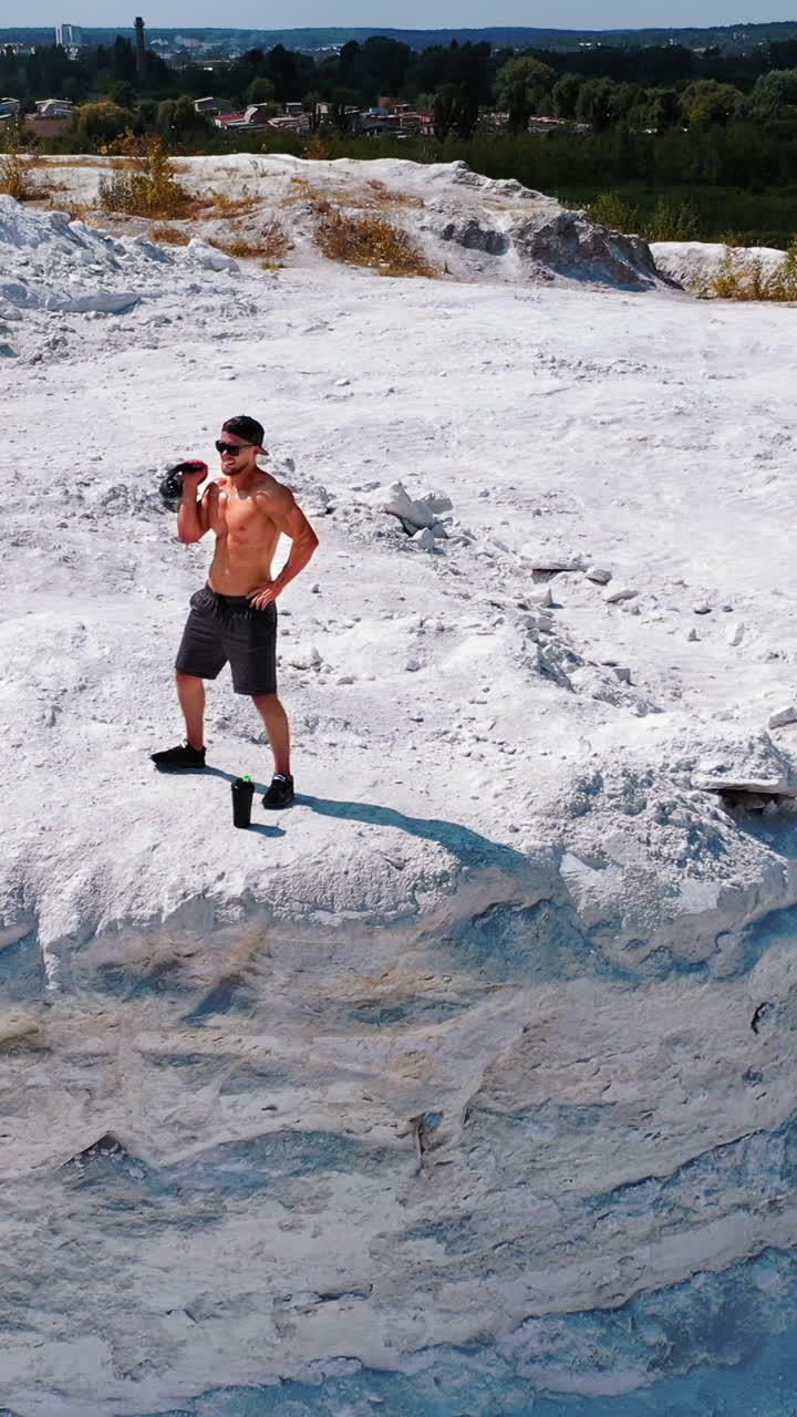 Brutal strong bodybuilder pumping up muscles. Bodybuilding and outdoor sports concept. Aerial view. Vertical video