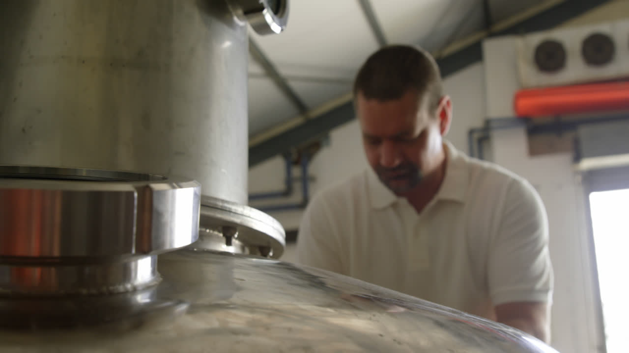 Male worker examining a distillation tank 4k