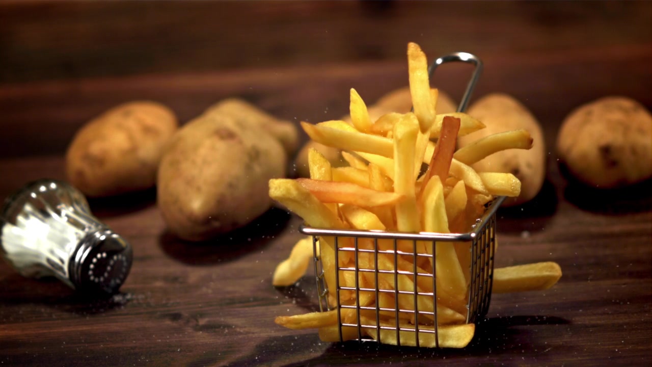 Batatas Fritas Douradas Caindo em uma Cesta de Metal em Câmera Lenta