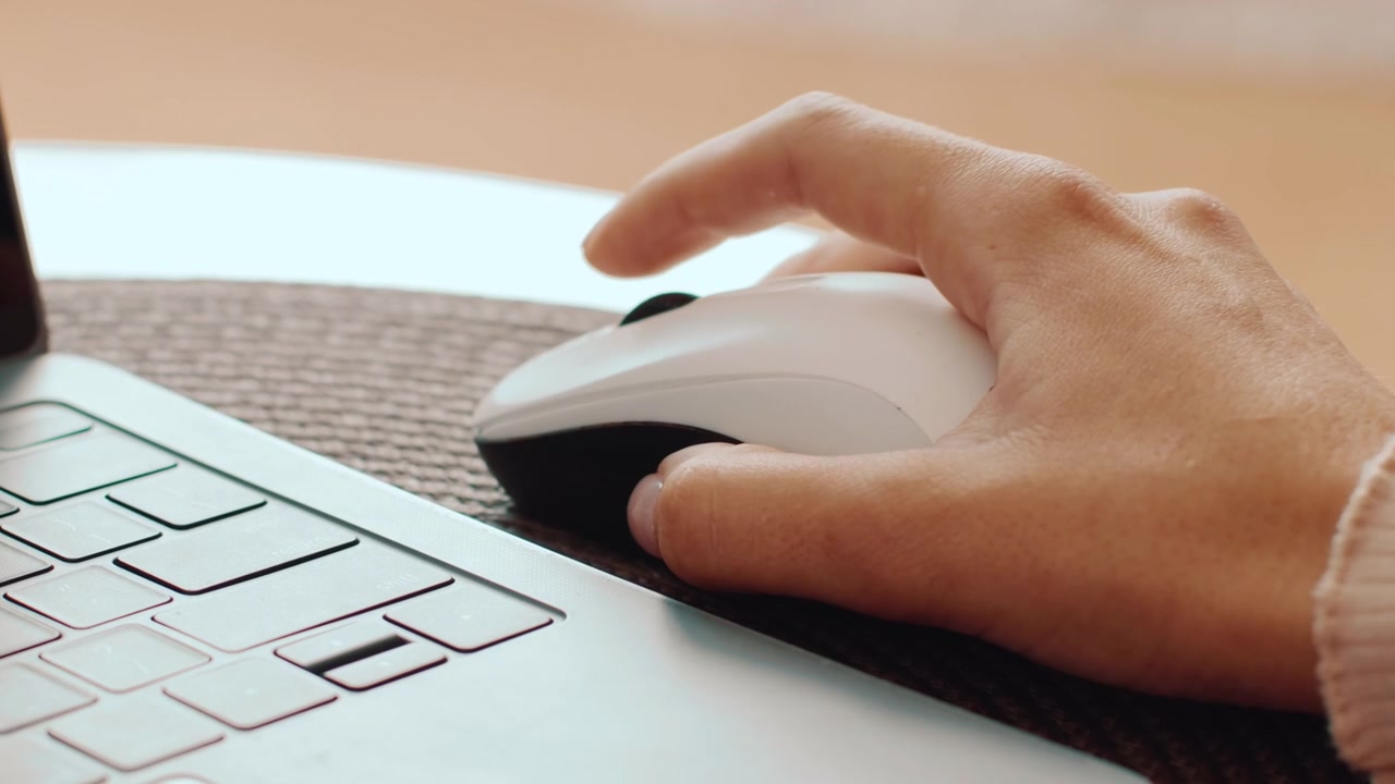 Close-up of a Person Using a Computer Mouse Next to a Laptop