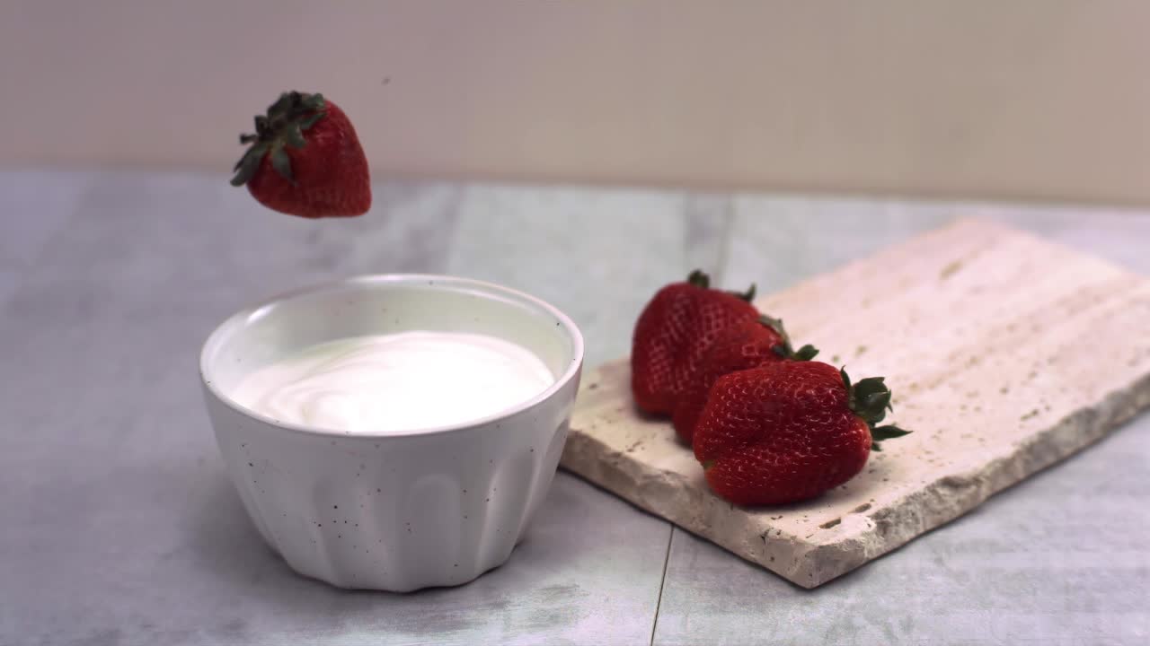 super cámara lenta de fresas frescas que caen en la crema a 1000 fps