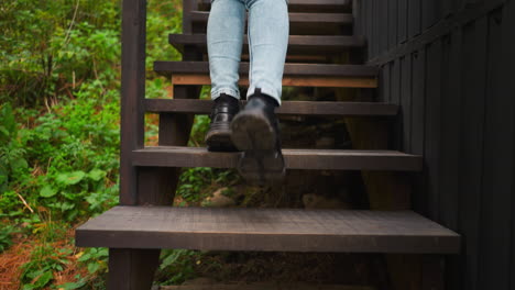 woman in sneakers stepping from stair to stair. young lady reaches top of stairs on way to gampling house. young woman during vacation in forest area