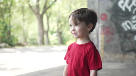 cámara moviéndose de derecha a izquierda para tomar una foto de un niño pequeño con una camiseta roja mirando hacia otro lado sonriendo con alegría