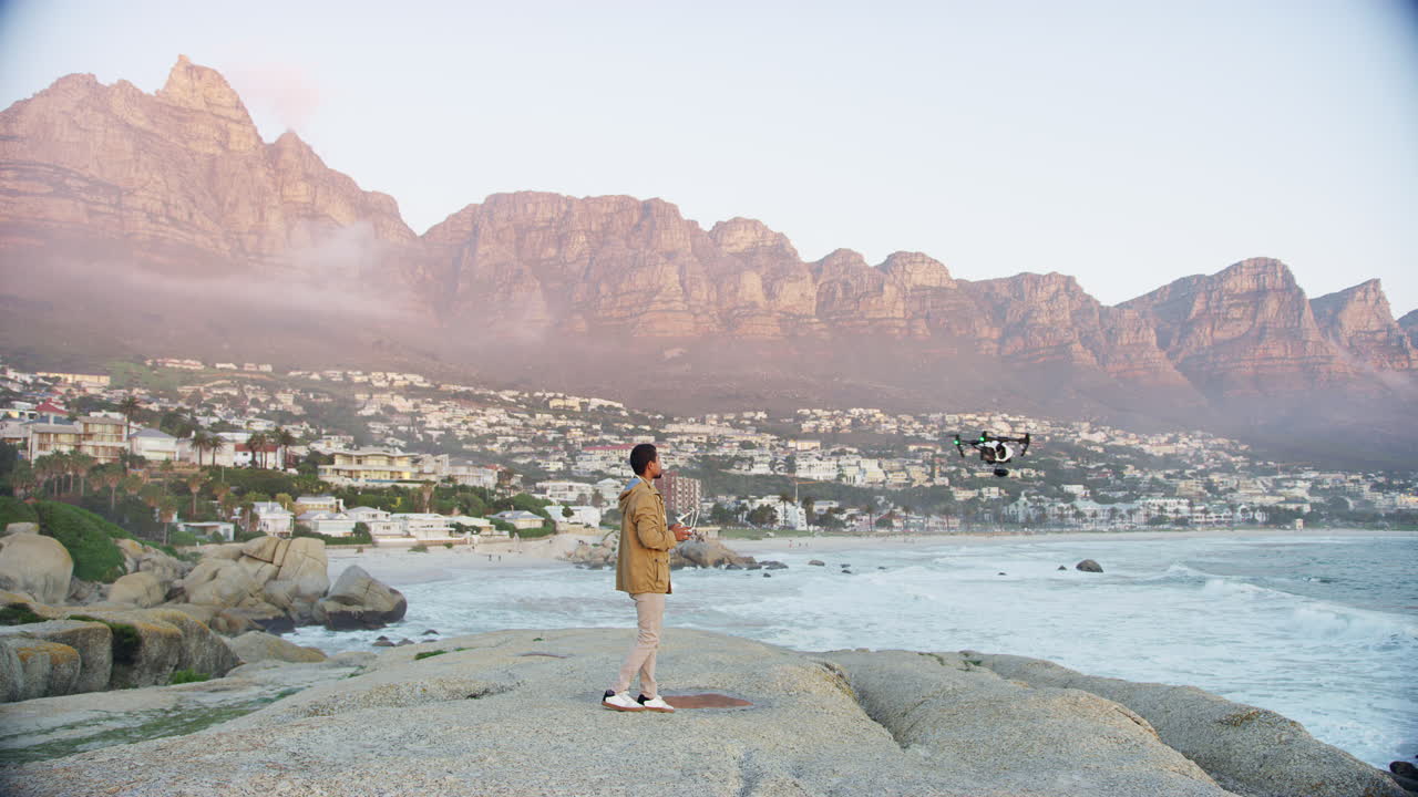 해변에서 드론을 조종하는 젊은 남자