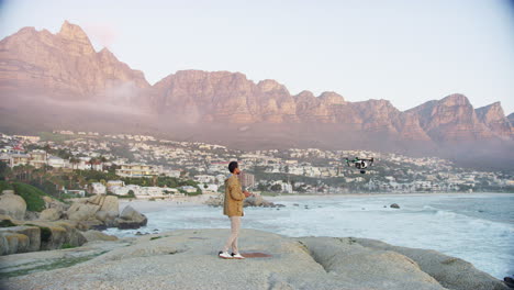 a young man flying a drone at the beach