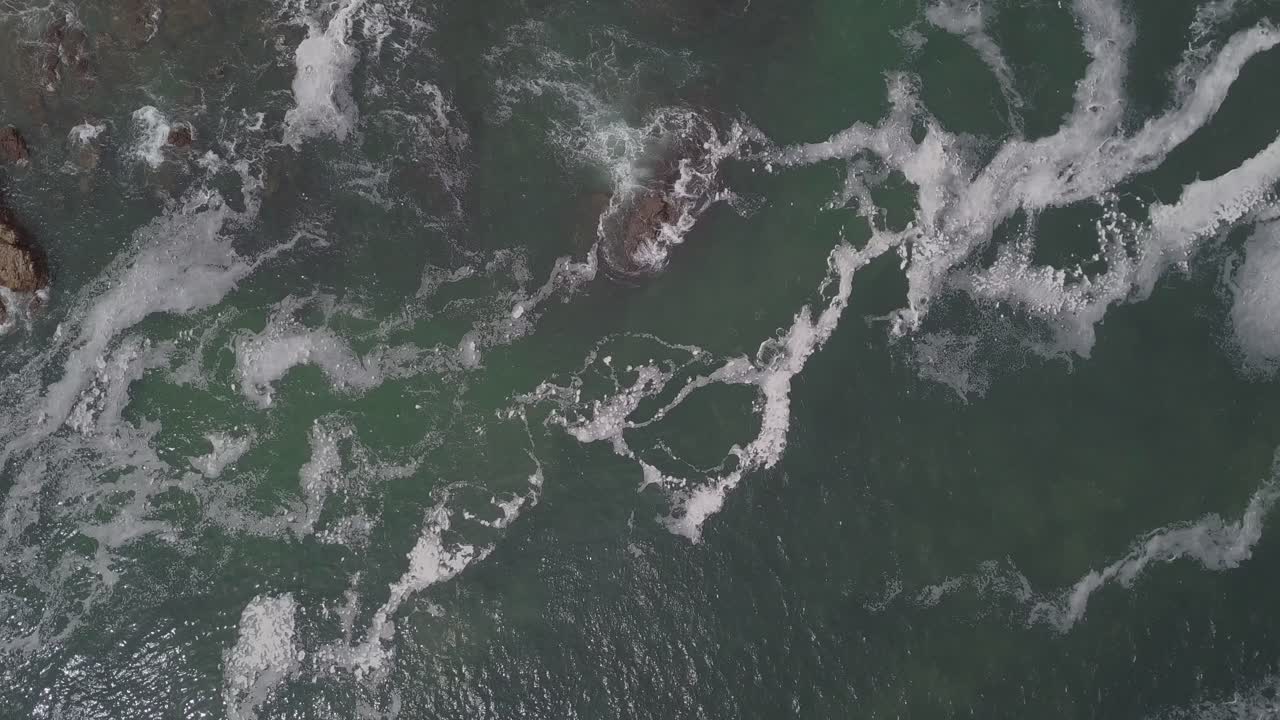 vista aérea vertical: espuma de agua de mar verde poco profunda en la marea de inundación