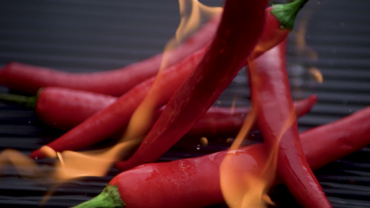 빨간  ⁇ 라페노 페퍼가 뜨거운 바비큐 그릴에 느린 영상으로 떨어지고, 불꽃이 일어납니다.
