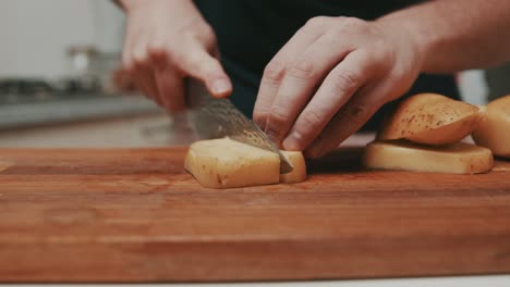 Chef-slices-thick-potato-chips-on-wooden-cutting-board