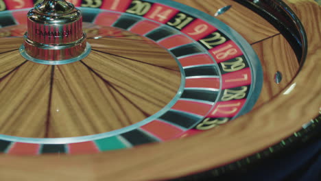 closeup of wooden roulette wheel rotating in foreground. table in luxury casino