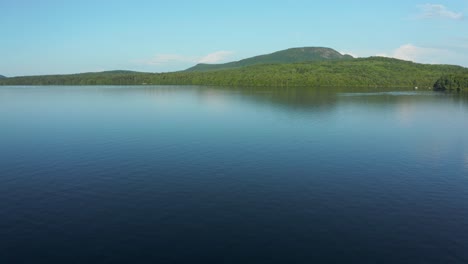 Drone-going-along-the-lake's-water-before-flying-up-and-away