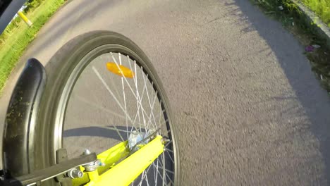 front wheel view of a yellow bicycle on the city road.