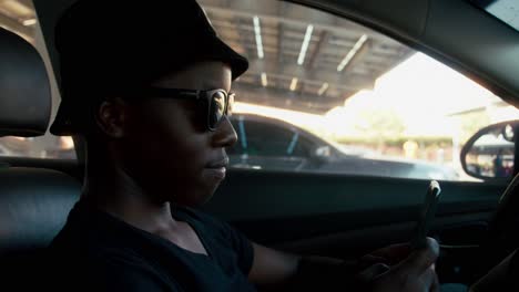 african american man typing a message on the phone while sitting in the car