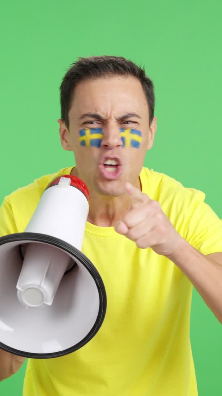 Excited man with swedish flag on face using a megaphone