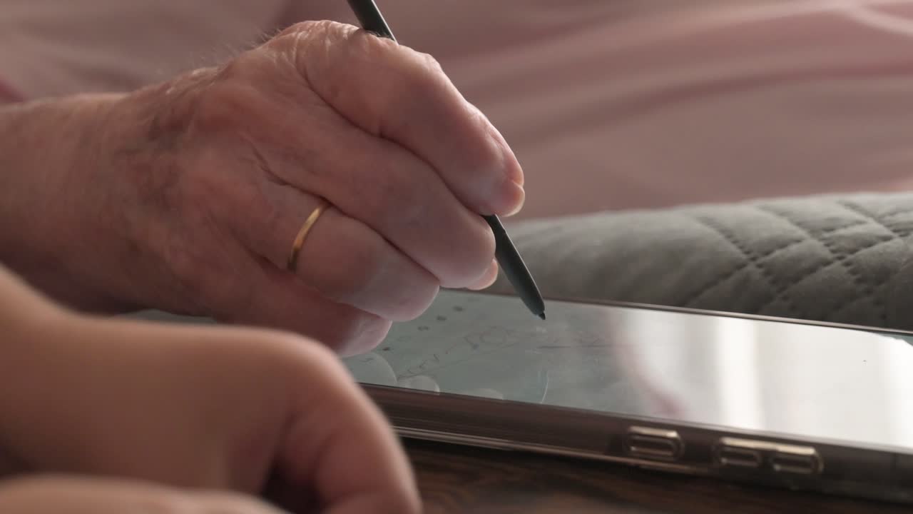 Elderly person drawing with a stylus on a smartphone while seated beside a child