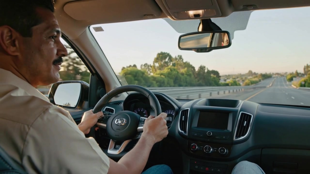 Hombre conduciendo, sujetando el volante, mirando el espejo y girándose hacia el pasajero después de una señal en el coche, con una botella de agua