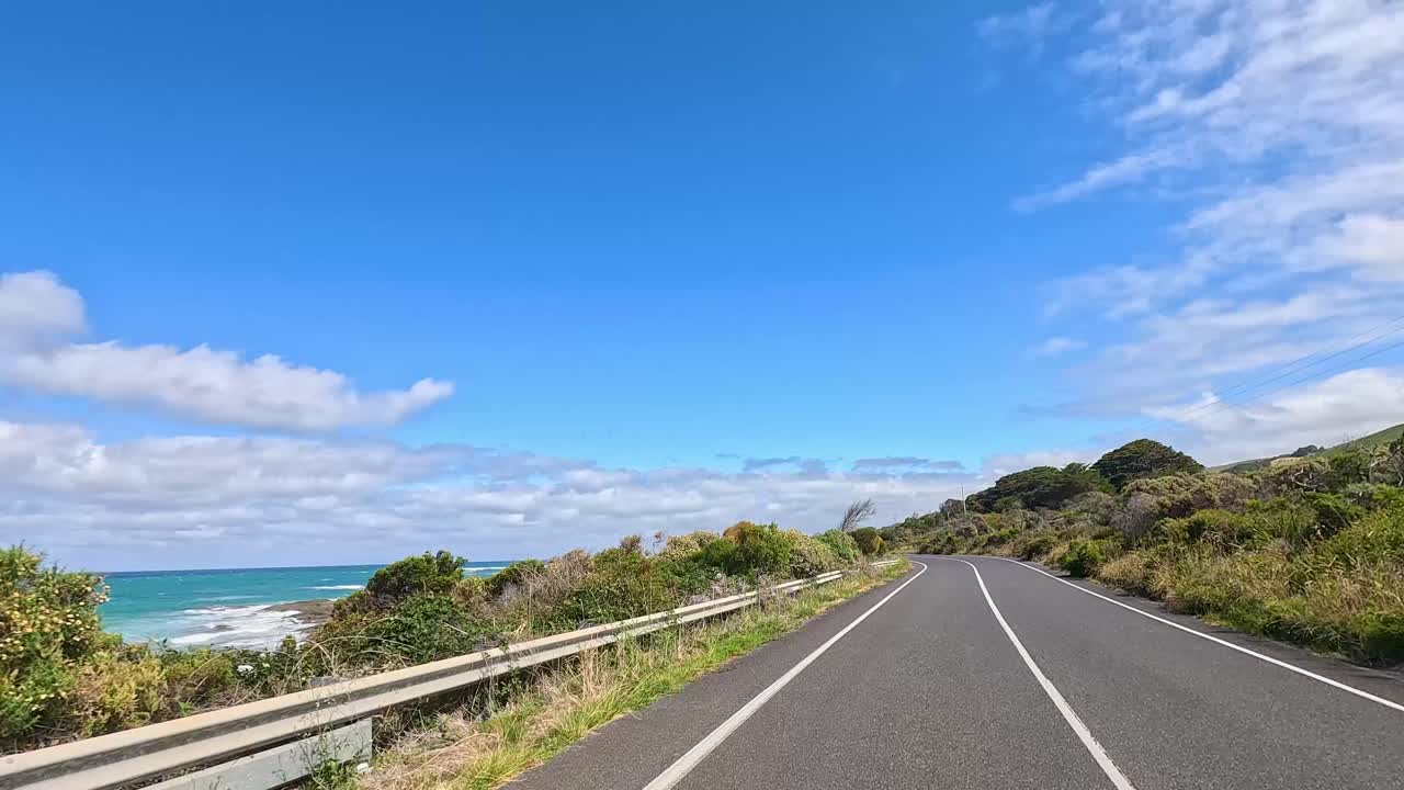 A 13-second video captures a drive along the Great Ocean Road, showcasing winding roads, lush greenery, and clear blue skies