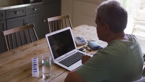 hombre de raza mixta senior que tiene una consulta médica en línea usando una computadora portátil