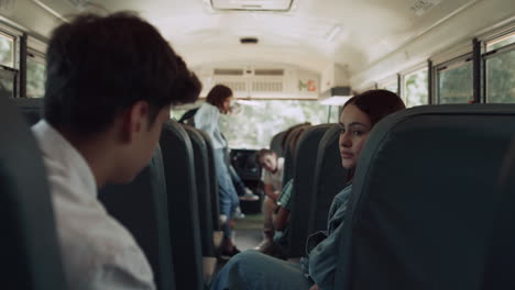 multiethnic classmates chatting ride school bus. kids wait schoolmates to board.