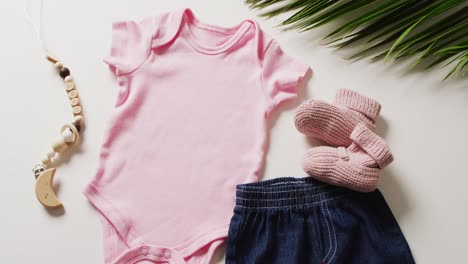 video of close up of pink baby grow, socks and skirt on white background