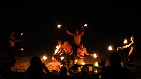 performers juggle fire on a beach at night