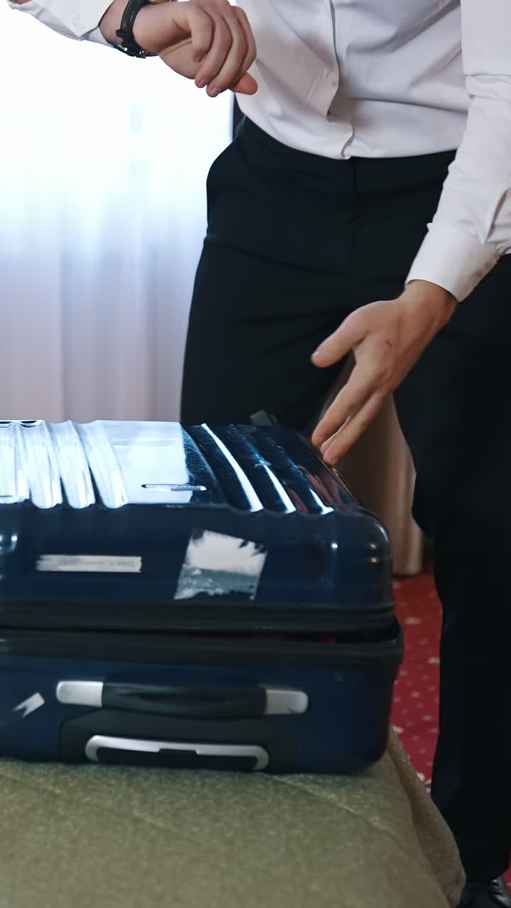 Packing suitcase in hotel room. Handsome young businessman packing his suitcase. Vertical video
