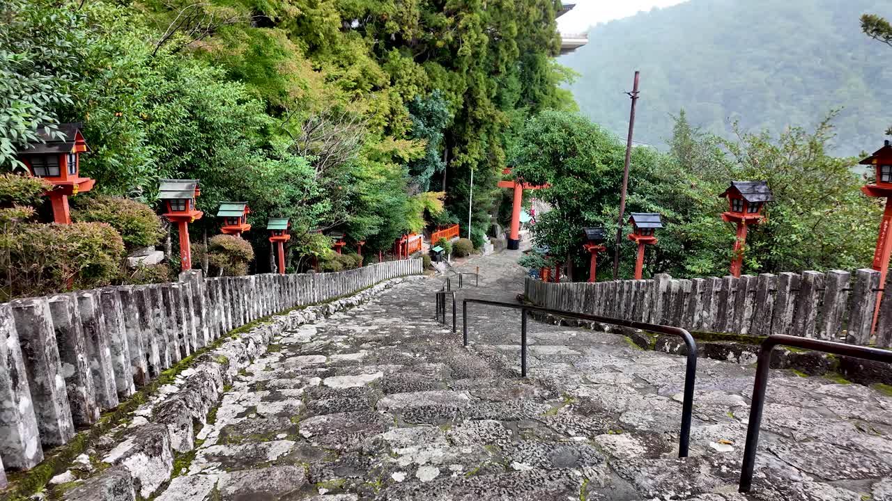 Pov descending stone stairs with red torii gate and traditional japanese lanterns at Kumano Nachi Taisha shrine in Wakayama Prefecture