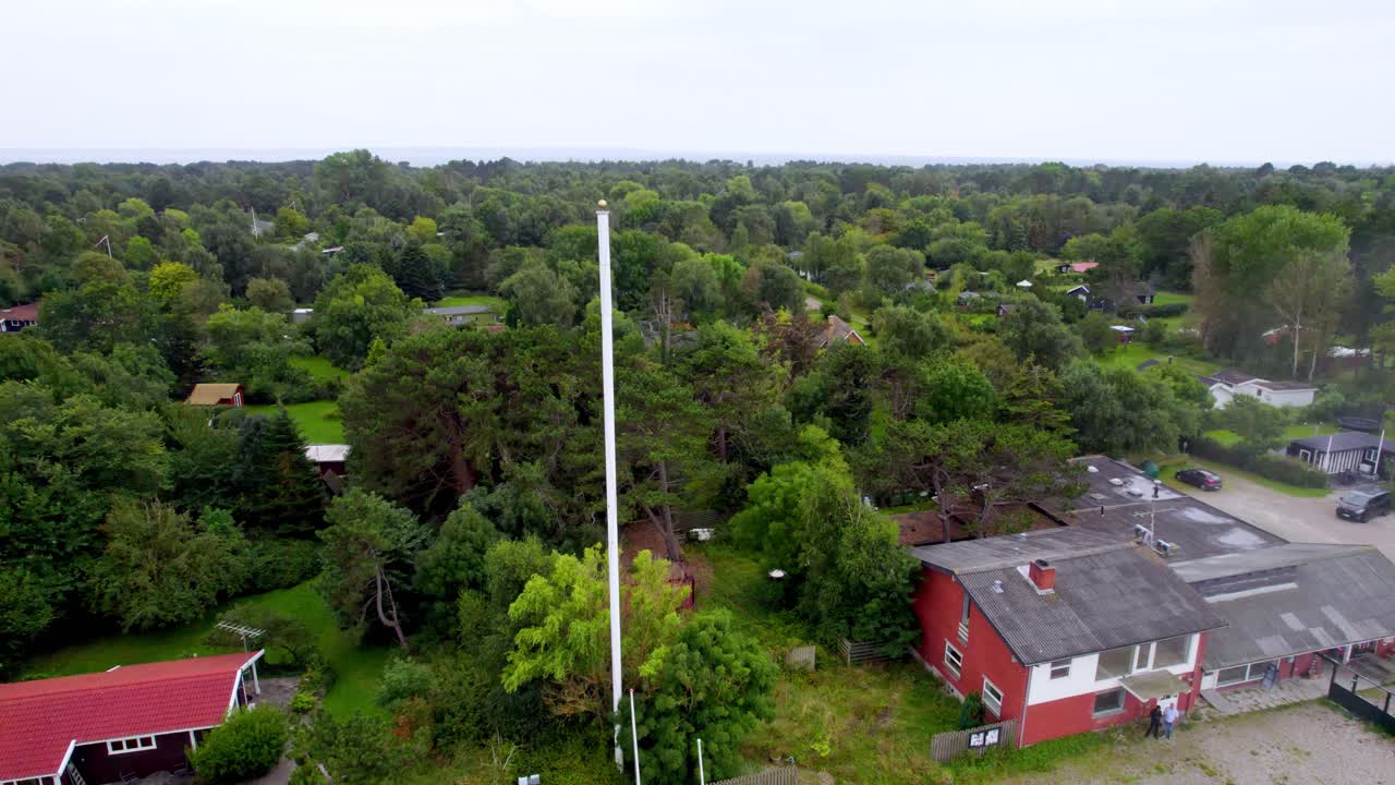 A scenic aerial shot captures a coastal road, lush greenery, and buildings on Funen island in Denmark on a calm day