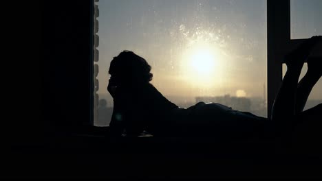 side-view-lady-with-long-hair-swings-legs-against-sunset