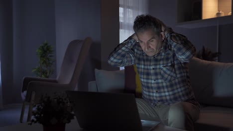 hombre trabajando desde casa mirando la computadora portátil y viendo algo que lo molesta y se enoja.