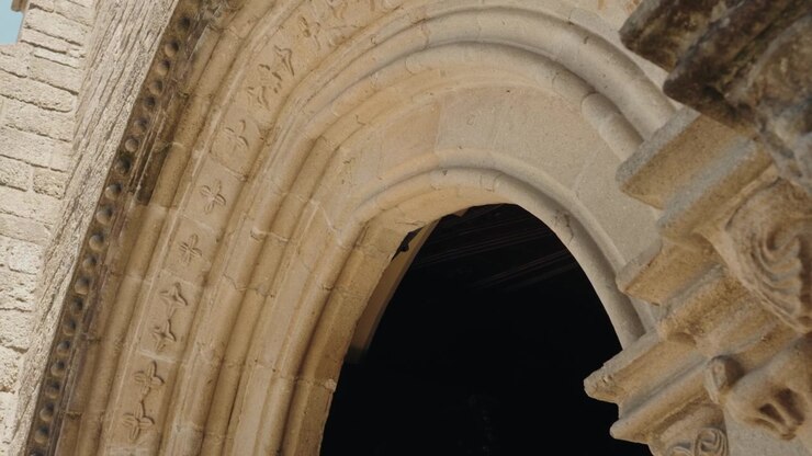 Arco e portale gotico in pietra intagliata e ornata su una facciata di chiesa storica in Portogallo.