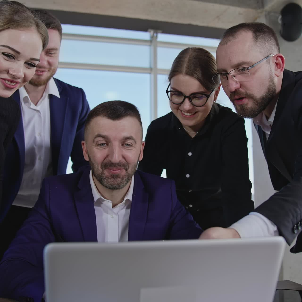 Working team gathered around laptop, look at it, discuss and smile. Colleagues building strategies and making suggestions. Office team involved in active work