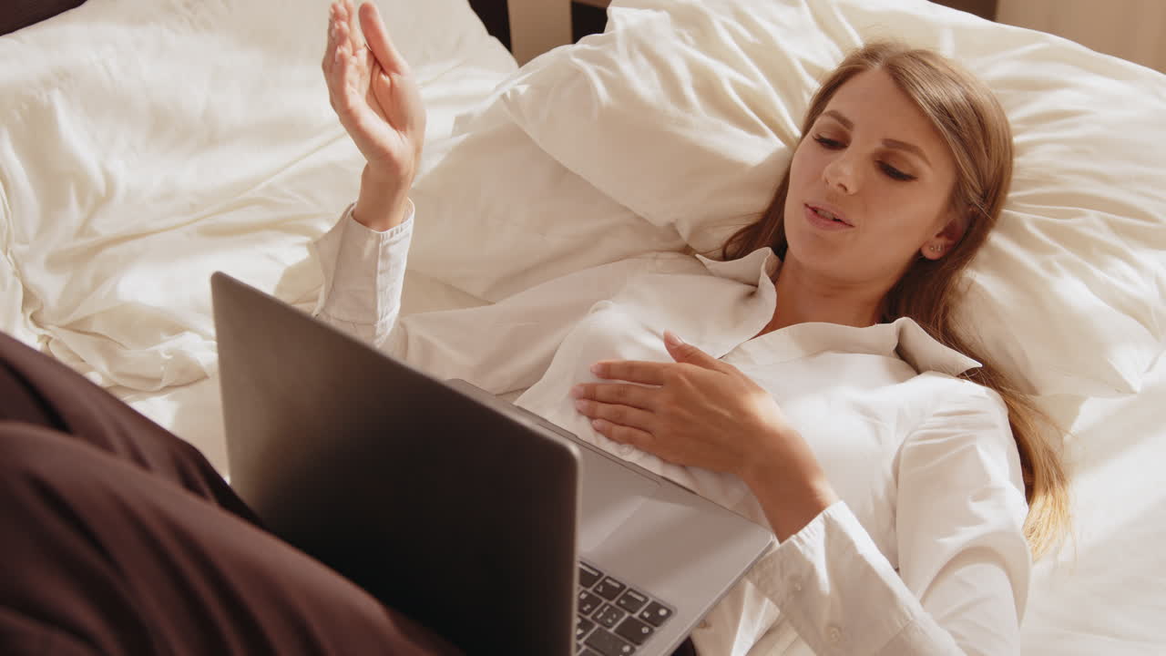 침대에 노트북으로 일하는 여자