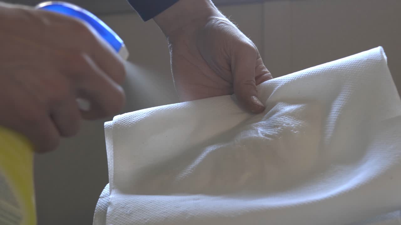 Spraying The Paper Tissue With Some Cleaning Agent Many Times. -close up shot