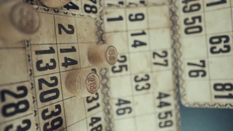 a vertical macro video of a bingo board, studio lights, 120 fps, slow motion, wooden chip digits, raw footage, vintage lottery desk game, card numbers, crane zoom in smooth movement