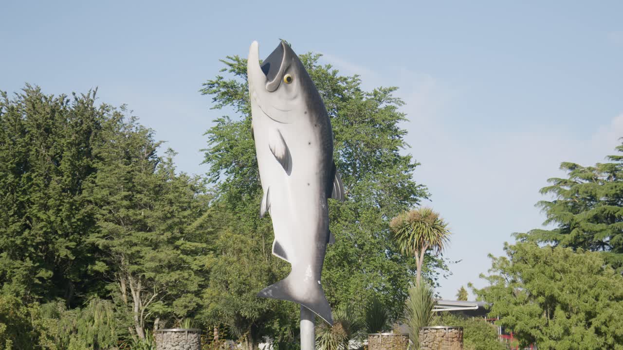 Static shot of the giant Salmon sculpture in Rakaia, New Zealand with cars and trucks driving past