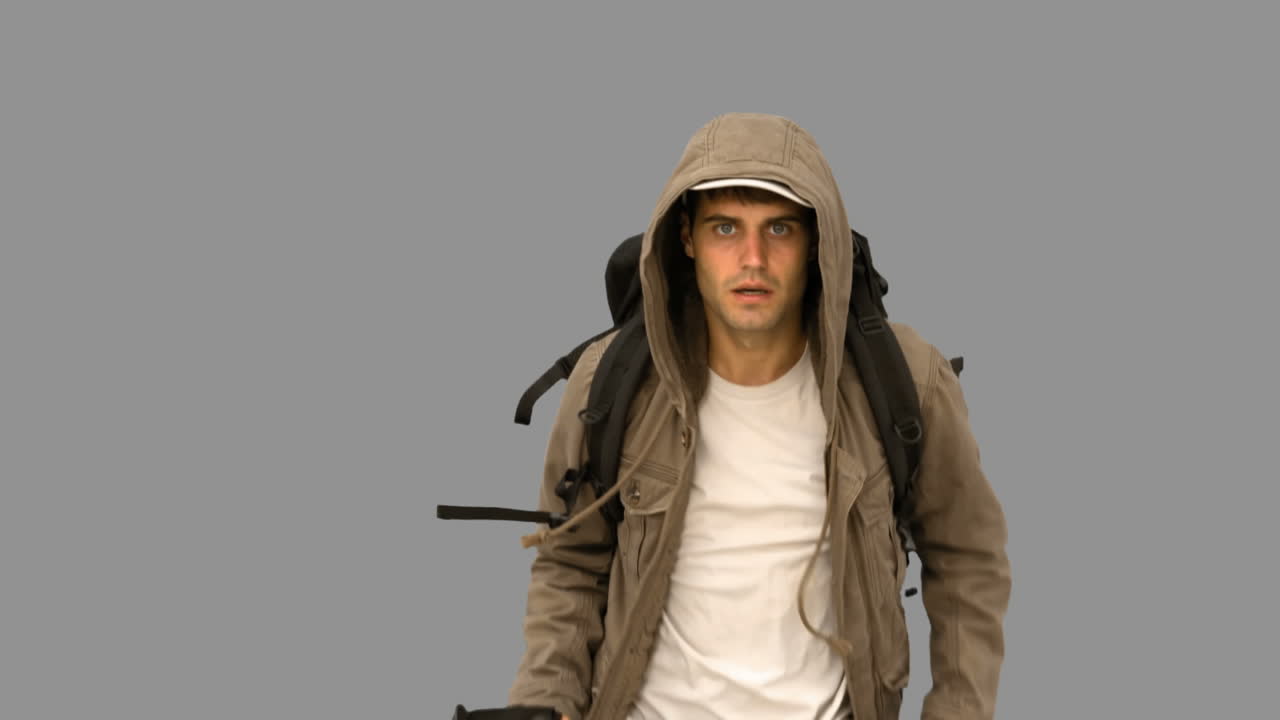 hombre con un abrigo y un bastón de senderismo corriendo en la pantalla gris