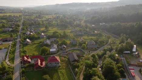 Vista-Aérea-Hacia-Casas-Idílicas,-En-La-Ciudad-De-Shayan,-Mañana-Soleada-Y-Brumosa,-En-Las-Montañas-De-Los-Cárpatos,-Ucrania---Descendiendo,-Disparo-De-Drones