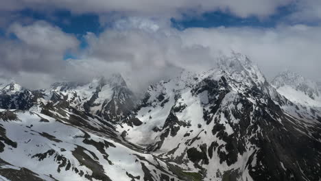 vuelo aéreo a través de nubes montañosas sobre hermosos picos nevados de montañas y glaciares.
