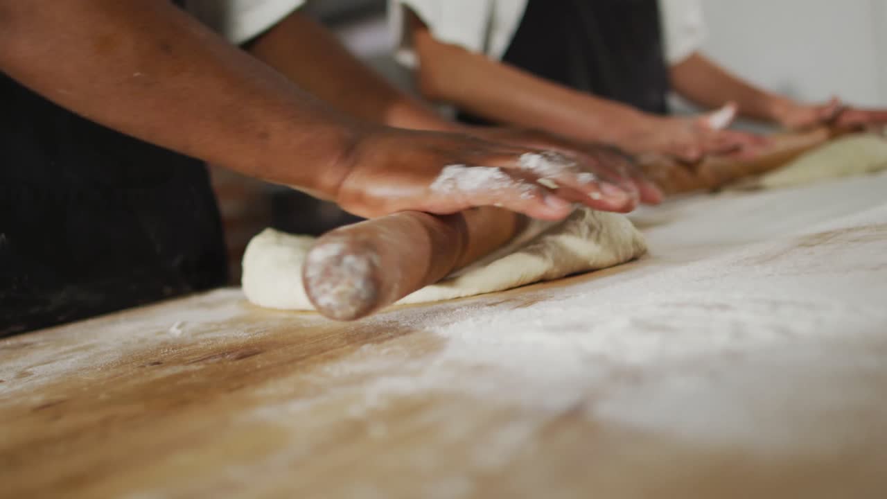 Animation of hands of diverse female and male bakers rolling sourdough for bread
