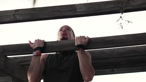 sportsman doing push-ups on a wooden beam in a park