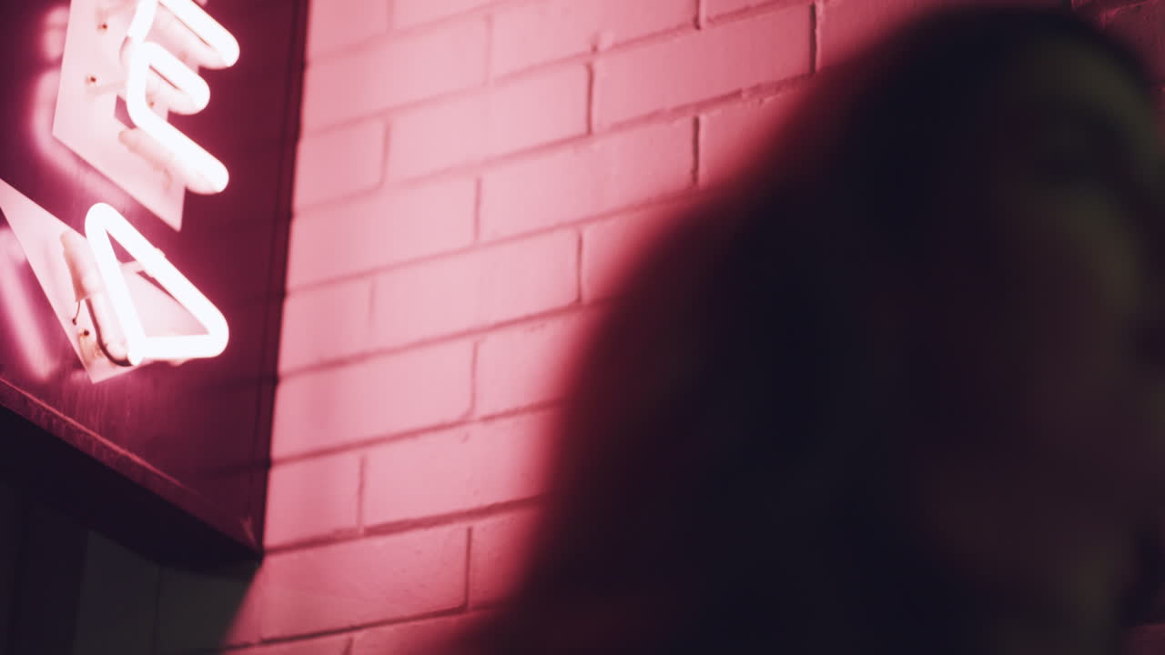 две женщины, указывающие на неоновый знак ночью