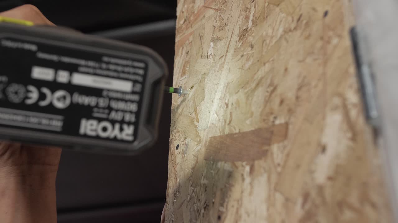 Drill driving a long screw into a wooden board for secure attachment