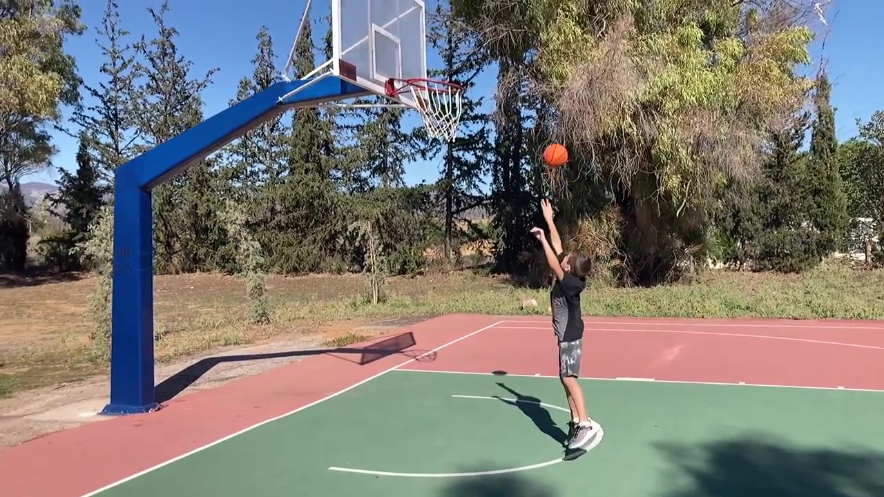 Un giovane ragazzo si esercita a fare canestro su un campo da basket all'aperto a Kifisia, Grecia