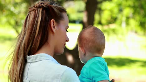 mother holding cute baby son in the park