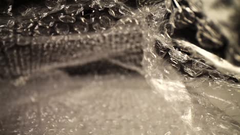 pushing into a bubble wrap bag, top of the bag flutters slightly, focused on the top third of the bag