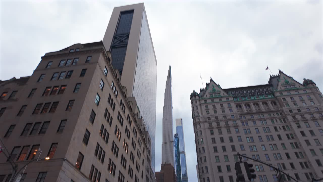 A street level view of Fifth Avenue by Bergdorf Goodman in NYC on a cloudy day. The camera tilt up looking up towards Billionaire's Row as people walking by with Fifth Avenue closed to vehicle traffic