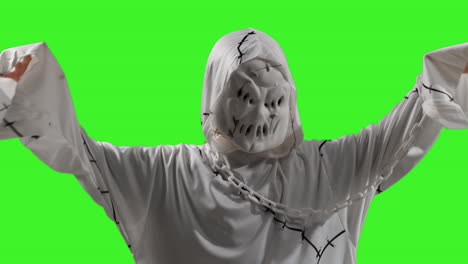 niño vestido de fantasma zombie monstruo disfraz de truco o trato en halloween asustando a la gente contra el fondo de la pantalla verde del estudio