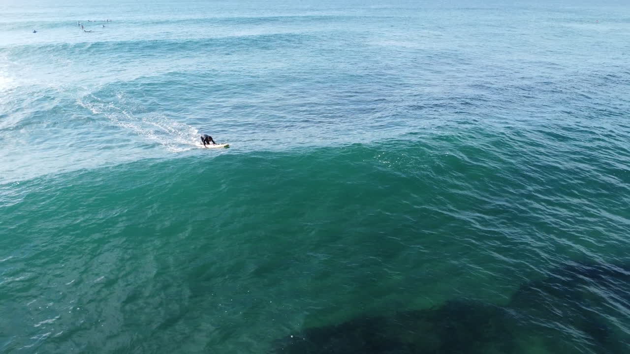 Lifesaver and surfer catches wave and does headstand captured on a drone.