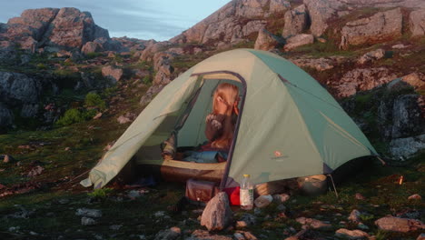 beautiful blonde girl brushing her hair in a stunning sunrise morning atmosphere in her tent, surrounded by a mountain landcape, romdalseggen, norway